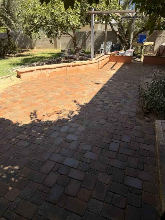 Paver patio in blended red, tan, and charcoal tones laid in a mixed-size pattern, partly in afternoon shade.