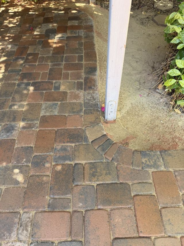 Close view of the multicolor patio edge, where a curved row of pavers turns the corner around a post.